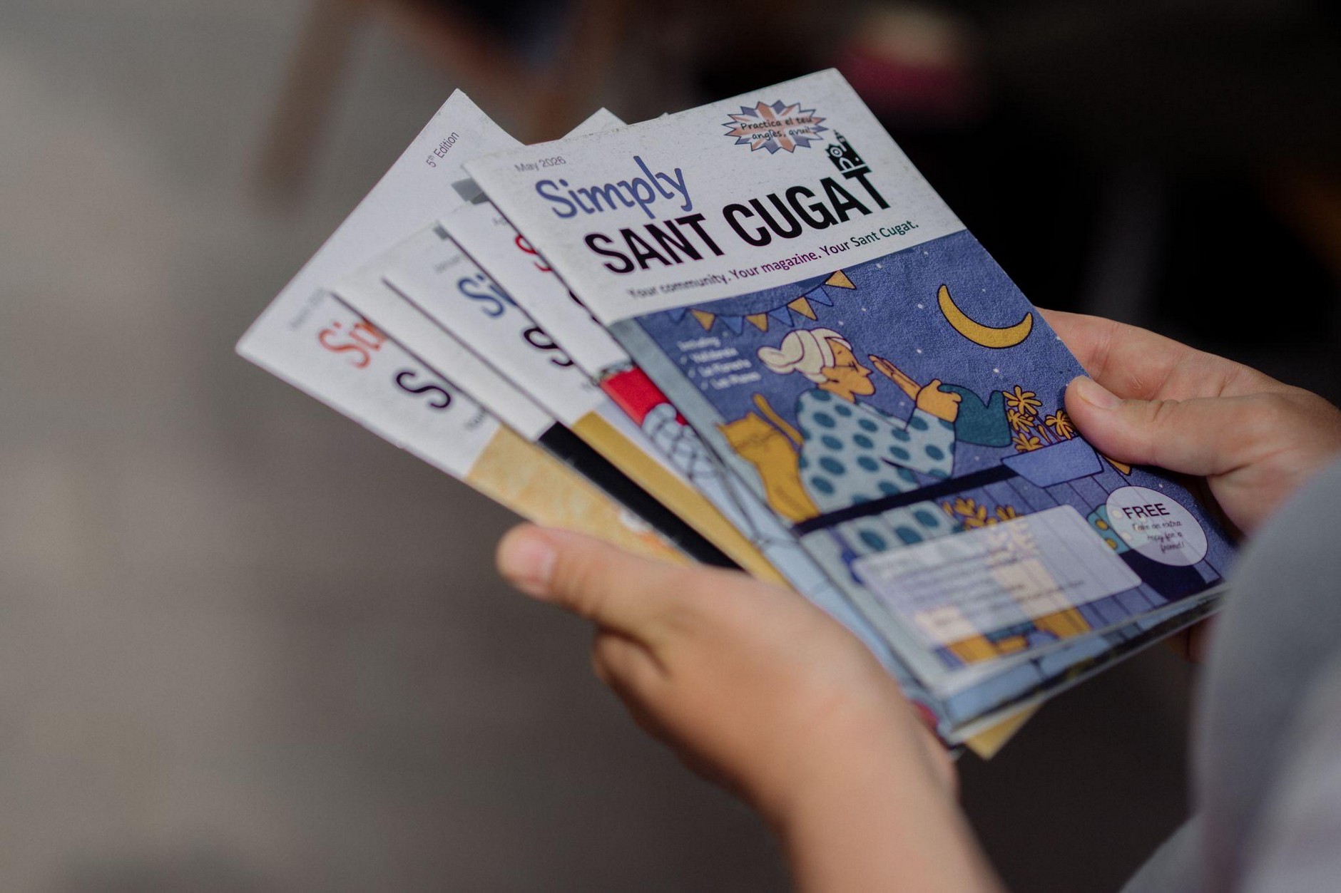 Hands holding copies of Simply Sant Cugat magazine